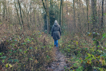 Woman walking in winter forest. Rear view. Nature reserve Needse