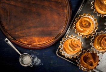 Modern fashionable pastries - scones cruffins  (puffmaffin), a mixture of a croissant and maffin. On blue dark wooden table, sprinkled with powdered sugar. Copy space, top view