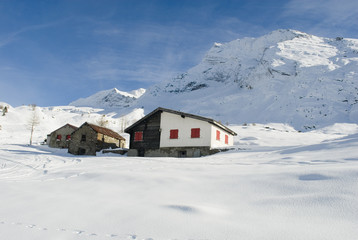 Piccola baita di montagna in legno e pietra nella neve fresca del passo del sempione, alpi svizzera