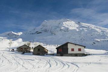 Piccola baita/chalet di montagna in legno e pietra nella neve fresca del passo del sempione, alpi svizzera