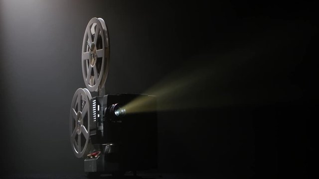 Projector illuminated by lights broadcasts a movies. Dark studio