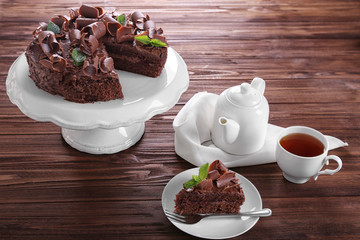 Delicious chocolate cake with tea on table