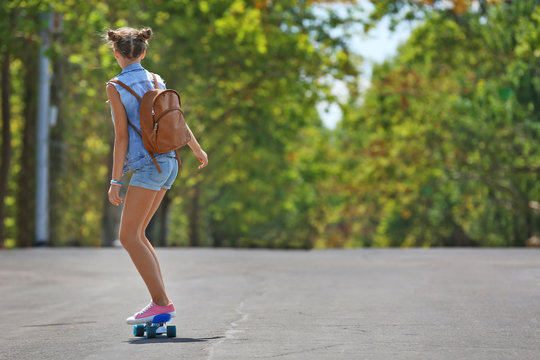 Cute Young Girl Riding Skateboard On Street