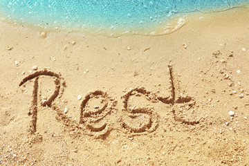 Word REST on beach sand