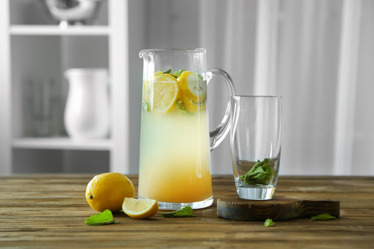 Glass jug with lemonade on wooden table