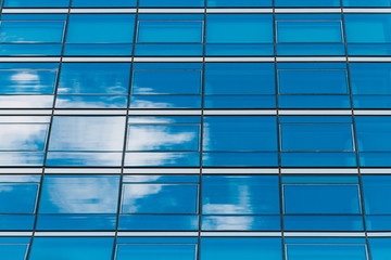 Office building with blue mirrored windows and reflection of clo