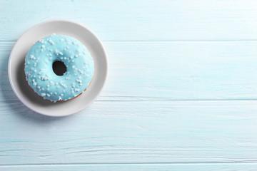 Tasty donut on plate on wooden background