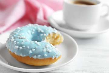 Plate with bitten donut and cup of coffee on background