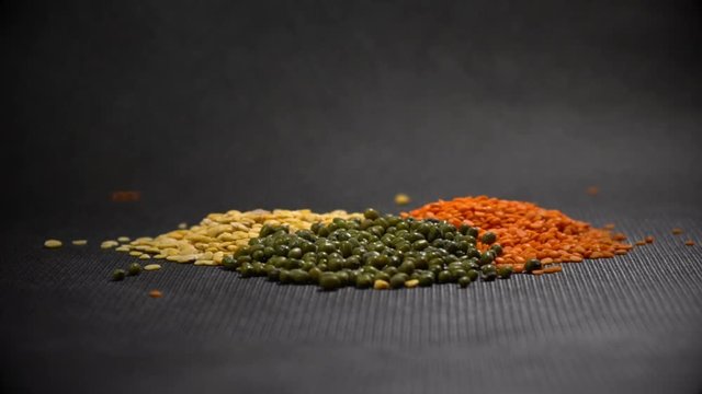 A rain from seeds drops on three bunches of lentils and mung in slow motion.