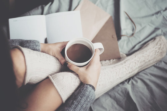 Woman holding cup of coffee in hands. Top view point, soft focus