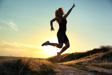 Silhouette of woman on sunset sky background