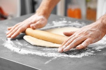 Male hands preparing dough for pizza on table closeup