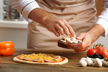 Obraz na płótnie Canvas Male hands preparing pizza at wooden table closeup