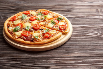 Fresh pizza with tomatoes, cheese and mushrooms on wooden background