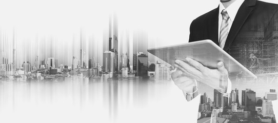 Businessman working on digital tablet, with double exposure city and real estate site construction, business development concept  - 130787072