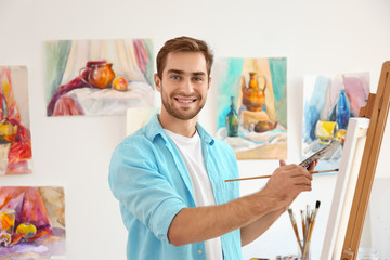 Young male artist painting picture in studio