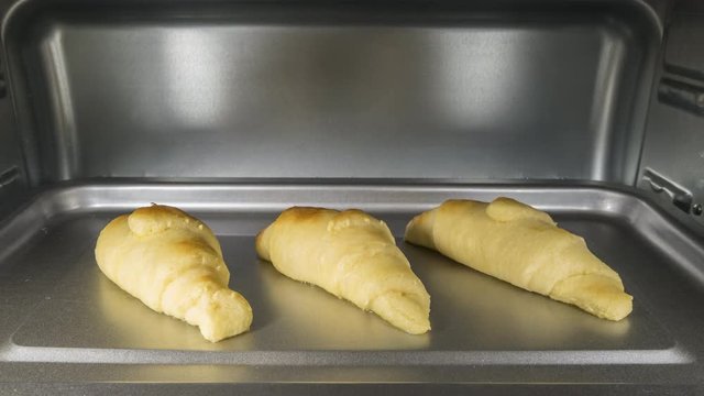 Time lapse of croissants cooking in oven.