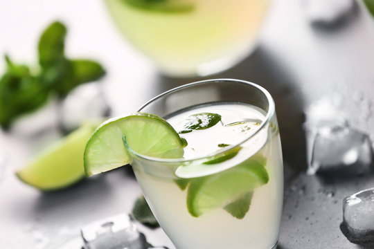 Fresh lime cocktail with ice cubes on grey background