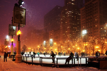Naklejka premium Zimowa noc w Chicago. Ludzie cieszący się na łyżwach w Millennium Park lodowisko podczas śnieżnej nocy w Chicago.