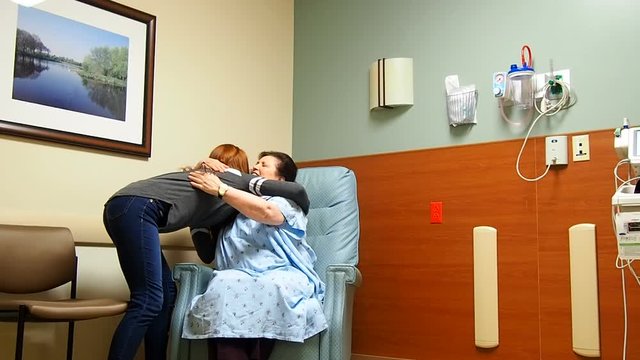 Young girl visiting with patient in hospital hugging and saying goodbye

