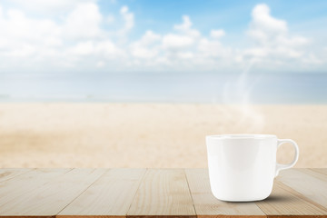 Hot coffee with smoke on wooden table top on blurred beach background