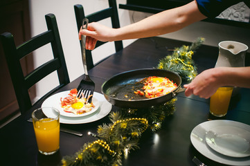 Woman puts homemade food. Female hands carefully applied to fried egg dish from  pan. breakfast for two persons, at home in kitchen at dining table