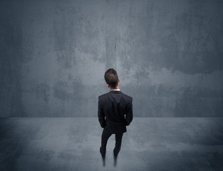 Obraz premium Businessman standing in front of urban wall