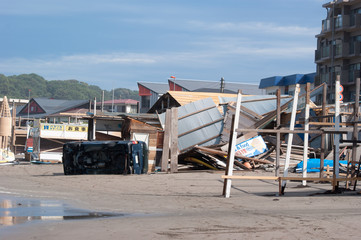 Fototapeta na wymiar 台風による強風で横転した海岸にある自動車と崩壊した海の家