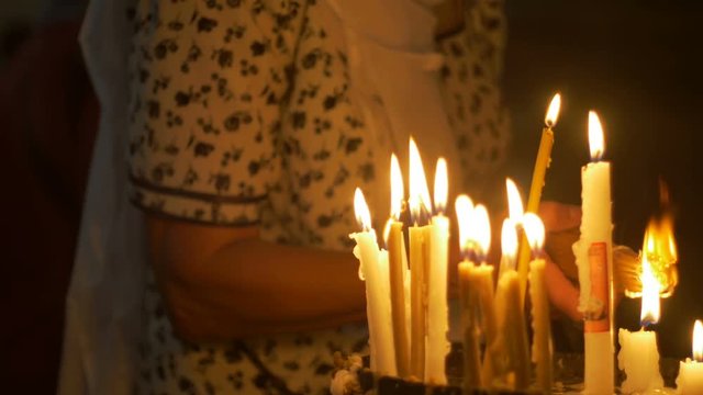 Close up of prayers hands lighting candles in the Holy Sepulchre Church in Jerusalem