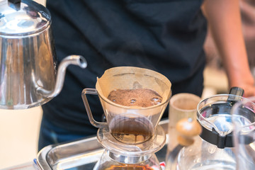 Hand drip coffee. Barista pouring water on coffee ground with filter. Hot coffee.
