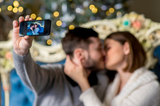 Couple of lovers taking selfie on smartphone in Christmas time