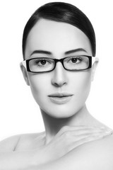 Fototapeta na wymiar Black and white portrait of young beautiful woman in stylish glasses over white background