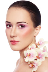Fototapeta premium Portrait of young beautiful woman with glowing make-up and orchid over white background