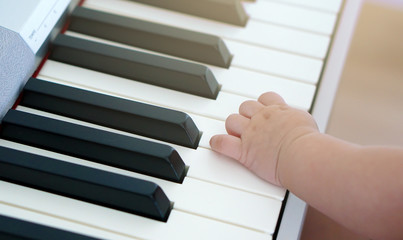 Fototapeta na wymiar Baby's little hand on piano keyboard