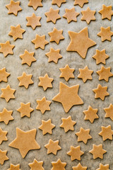 Pattern of stars shaped cookies on parchment paper background. Christmas, New Year, holidays concept. Vertical composition, top view