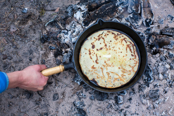 Cooking pancakes on the fire in the forest.
