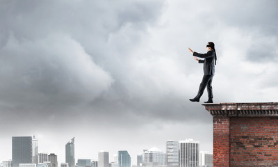 Danger and risk concept with businessman making step from edge