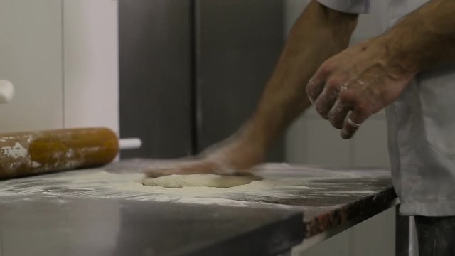 Cook makes a basis for pizza on kitchen