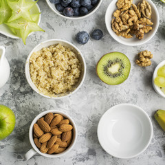 Healthy fresh breakfast. Granola, quinoa bowl, various nuts and fruit skewers with green fruits on a dark background. Top view. Color year. Greenery. 