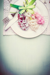 Spring table setting with plate, cutlery, ribbon and pretty hyacinths flowers , top view, border, pastel color