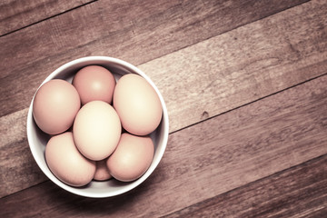 Fresh eggs in cup on wooden background.