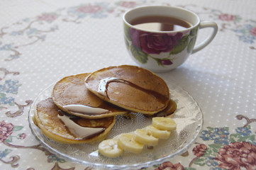 Photo of cup of tea with muffins and banana slices on a plate