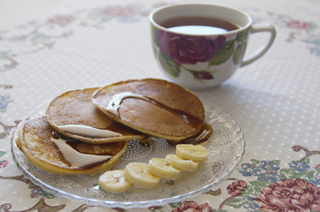 Photo of cup of tea with muffins and banana slices on a plate