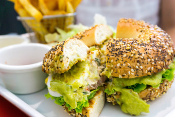 Bagel with fresh cheese and fresh lettuce on table