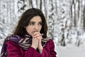 Fototapeta na wymiar Girl in a red coat and headscarf on the background of snow-covered trees