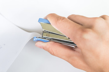 closeup of hand using stapler machine with paper on white background
