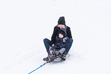 Fototapeta na wymiar Mother with the little girl ride sledge.