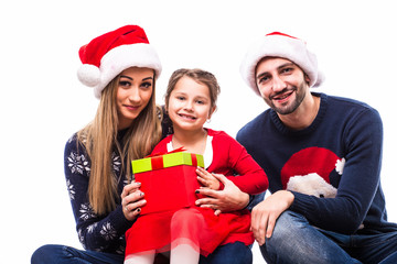 Young daughter get Christmas gift near mother and father on white background.