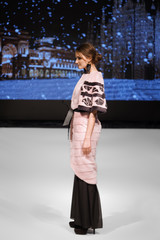 Fashion model stands in profile on runway in fur coat