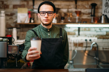 Barman in black apron stretches plastic cup
